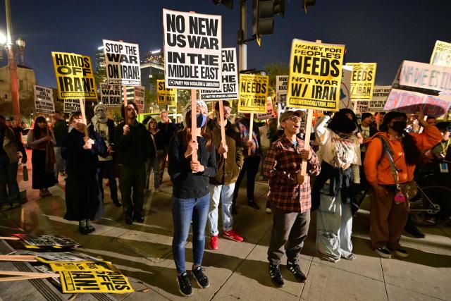 Demonstrators hold placards as they rally during a protest against military action in Iran outside of City Hall in Los Angeles, California, on March 2, 2026. New strikes were reported on March 2 across the Middle East, including Israeli strikes on Lebanon and a drone attack on the US embassy in Saudi Arabia's capital Riyadh. The conflict started by US and Israeli strikes on Iran over the weekend, which sparked retaliatory Iranian attacks across the region, showed no sign of abating as it entered its fourth day. (Photo by Frederic J. Brown / AFP)