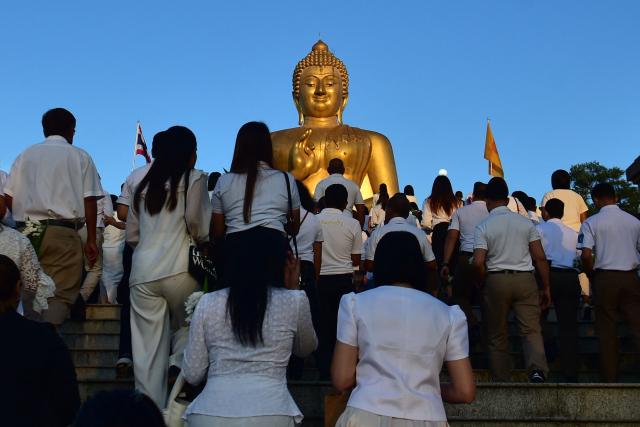 Buddhist devotees walk up to a giant Buddha statue during an event to mark Makha Bucha Day in the southern Thai town of Narathiwat on March 3, 2026. (Photo by Madaree TOHLALA / AFP)