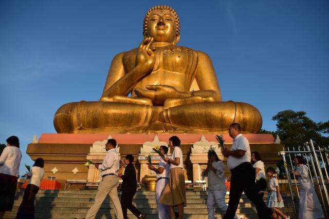 Buddhist devotees walk around a giant Buddha statue during an event to mark Makha Bucha Day in the southern Thai town of Narathiwat on March 3, 2026. (Photo by Madaree TOHLALA / AFP)