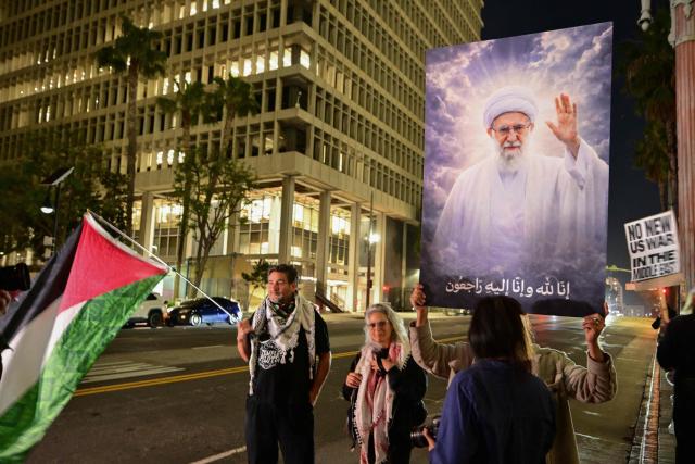 A demonstrator holds an image of late Iran's Supreme Leader Ayatollah Ali Khamenei while another waves a Palestine flag during a protest against military action in Iran outside of City Hall in Los Angeles, California, on March 2, 2026. New strikes were reported on March 2 across the Middle East, including Israeli strikes on Lebanon and a drone attack on the US embassy in Saudi Arabia's capital Riyadh. The conflict started by US and Israeli strikes on Iran over the weekend, which sparked retaliatory Iranian attacks across the region, showed no sign of abating as it entered its fourth day. (Photo by Frederic J. Brown / AFP)