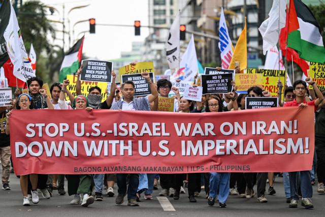 Activists hold placards during a rally condemning the US-Israeli strikes on Iran, near the US embassy in Manila on March 3, 2026. (Photo by Jam STA ROSA / AFP)