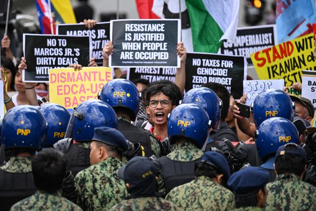Activists hold placards during a rally condemning the US-Israeli strikes on Iran, near the US embassy in Manila on March 3, 2026. (Photo by Jam STA ROSA / AFP)