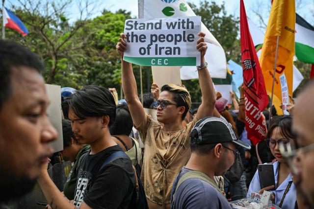 Activists hold placards during a rally condemning the US-Israeli strikes on Iran, near the US embassy in Manila on March 3, 2026. (Photo by Jam STA ROSA / AFP)