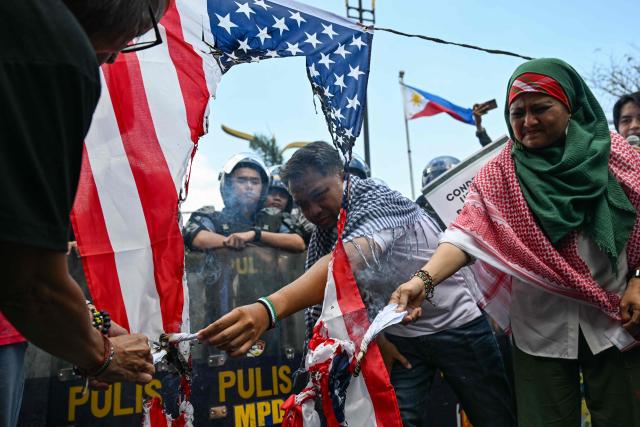 Activists burn a US flag during a rally condemning the US-Israeli strikes on Iran, near the US embassy in Manila on March 3, 2026. (Photo by Jam STA ROSA / AFP)