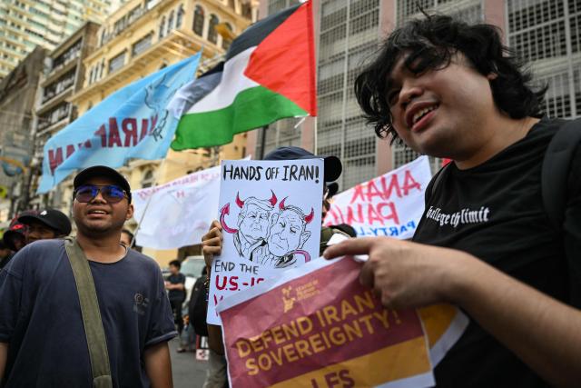 Activists hold placards during a rally condemning the US-Israeli strikes on Iran, near the US embassy in Manila on March 3, 2026. (Photo by Jam STA ROSA / AFP)
