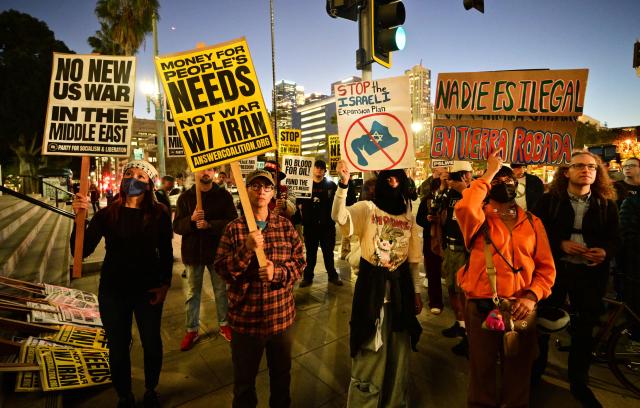 Demonstrators hold placards as they rally during a protest against military action in Iran outside of City Hall in Los Angeles, California, on March 2, 2026. New strikes were reported on March 2 across the Middle East, including Israeli strikes on Lebanon and a drone attack on the US embassy in Saudi Arabia's capital Riyadh. The conflict started by US and Israeli strikes on Iran over the weekend, which sparked retaliatory Iranian attacks across the region, showed no sign of abating as it entered its fourth day. (Photo by Frederic J. BROWN / AFP)
