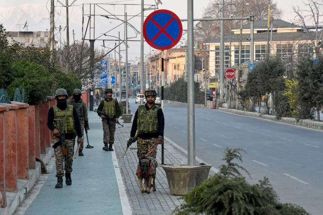 Security personnel patrol a street with a sniffer dog in Srinagar on March 3, 2026 as authorities imposed restrictions across the region amid protests over the death of Iran's supreme leader Ayatollah Ali Khamenei by US-Israel strikes. (Photo by Habib NAQASH / AFP)
