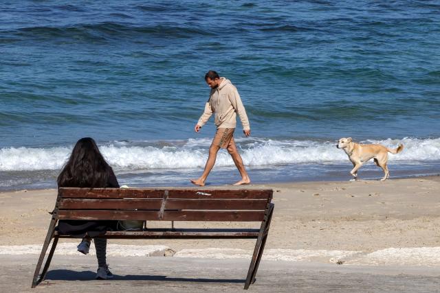 A dog walks behind a man along the beachfront in Tel Aviv on March 3, 2026. The United States and Israel started striking Iran on February 28, killing Iran's supreme leader and top military leaders, and prompting authorities to retaliate with strikes on Israel and across the Gulf. (Photo by Jack GUEZ / AFP)