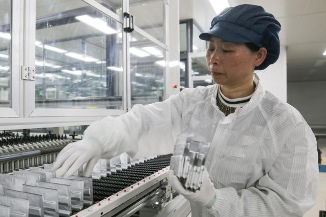 A woman works on lithium batteries for export orders at Yunqi Lithium Energy's factory in the high-tech zone of Suichuan county, in China's eastern Jiangxi province, on March 2, 2026. (Photo by CN-STR / AFP) / China OUT