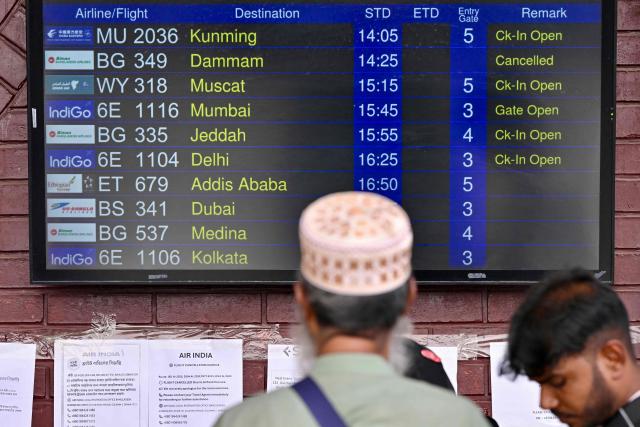 A passenger looks at a flight information board at the Hazrat Shahjalal International Airport in Dhaka on March 3, 2026 after carriers cancelled flights amid the Middle East conflict. The biggest disruption to global air transport since the Covid pandemic snarled travel for a fourth day on March 3, with thousands of flights affected and busy Gulf hubs including Dubai and Doha shuttered as Iran lashed out after US-Israeli strikes. (Photo by Munir UZ ZAMAN / AFP)