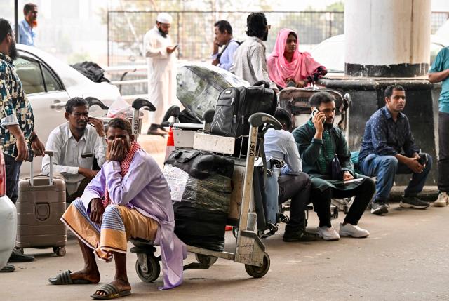 Stranded passengers wait with their luggage outside the Hazrat Shahjalal International Airport in Dhaka on March 3, 2026 after carriers cancelled flights amid the Middle East conflict. The biggest disruption to global air transport since the Covid pandemic snarled travel for a fourth day on March 3, with thousands of flights affected and busy Gulf hubs including Dubai and Doha shuttered as Iran lashed out after US-Israeli strikes. (Photo by MUNIR UZ ZAMAN / AFP)