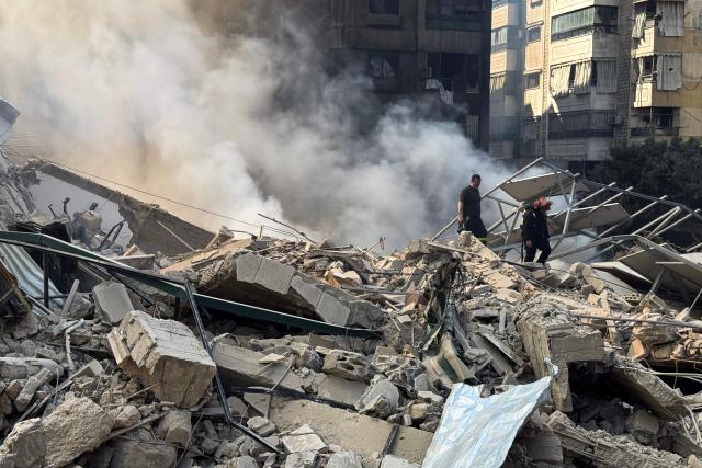 Firefighters inspect destruction at a site of an Israeli airstrike in the southern suburbs of Beirut on March 3, 2026. The war launched by the United States and Israel against Iran spread across the Middle East, threatening to plunge the global economy into chaos, with Lebanon and Gulf energy exporters dragged into the conflict. (Photo by AFP stringer / AFP)