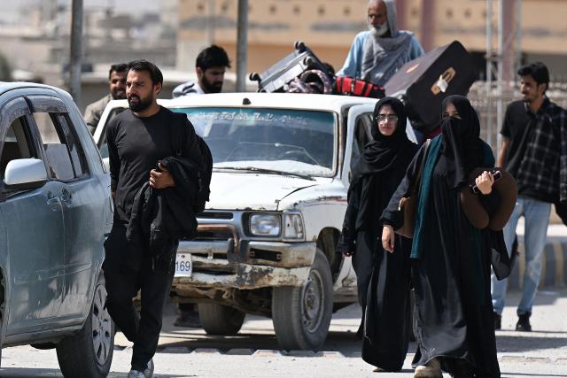 Pakistanis walk across the Taftan border as they return from Iran, in Balochistan province on March 3, 2026 amid ongoing US-Israel strikes on Iran. Pakistani nationals hauled suitcases across the border from neighbouring Iran, describing missiles being launched and travel chaos as they scrambled to leave the country after the US and Israel launched strikes over the weekend. (Photo by Banaras KHAN / AFP)