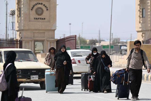 Pakistanis walk across the Taftan border as they return from Iran, in Balochistan province on March 3, 2026 amid ongoing US-Israel strikes on Iran. Pakistani nationals hauled suitcases across the border from neighbouring Iran, describing missiles being launched and travel chaos as they scrambled to leave the country after the US and Israel launched strikes over the weekend. (Photo by Banaras KHAN / AFP)
