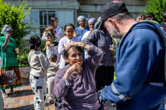 A first-responder speaks with a wheelchair-bound woman as security personnel conduct a search after a projectile hit the area of Petah Tikva in central Israel on March 3, 2026. The United States and Israel started striking Iran on February 28, killing Iran's supreme leader and top military leaders, and prompting authorities to retaliate with strikes on Israel and across the Gulf. (Photo by Ilia YEFIMOVICH / AFP)