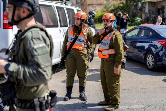 Israeli army soldiers stand by as security personnel conduct a search after a projectile hit the area of Petah Tikva in central Israel on March 3, 2026. The United States and Israel started striking Iran on February 28, killing Iran's supreme leader and top military leaders, and prompting authorities to retaliate with strikes on Israel and across the Gulf. (Photo by Ilia YEFIMOVICH / AFP)