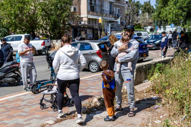 Members of a family gather outside a building as security personnel conduct a search after a projectile hit the area of Petah Tikva in central Israel on March 3, 2026. The United States and Israel started striking Iran on February 28, killing Iran's supreme leader and top military leaders, and prompting authorities to retaliate with strikes on Israel and across the Gulf. (Photo by Ilia YEFIMOVICH / AFP)