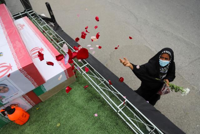 In this picture obtained from Iran's ISNA news agency, a mourner sprays flower petals on the coffins of children who were killed in a reported strike on a primary school in Irans Hormozgan province during a funeral in Minab on March 3, 2026. Iranian media have reported hundreds of Iranian casualties, including at a girl's school, although AFP reporters have not been able to verify tolls independently. The war launched by the United States and Israel against Iran spread across the Middle East, threatening to plunge the global economy into chaos, with Lebanon and Gulf energy exporters dragged into the conflict. (Photo by AMIRHOSSEIN KHORGOOEI / ISNA / AFP)