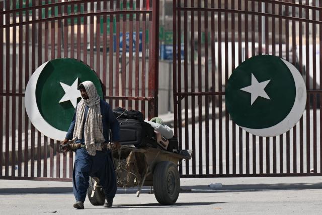 A porter pulls a cart loaded with suitcases at the Taftan border as Pakistanis return from Iran, in Balochistan province on March 3, 2026 amid ongoing US-Israel strikes on Iran. Pakistani nationals hauled suitcases across the border from neighbouring Iran, describing missiles being launched and travel chaos as they scrambled to leave the country after the US and Israel launched strikes over the weekend. (Photo by Banaras KHAN / AFP)