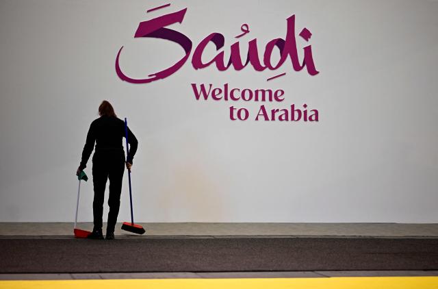 A woman with a broom cleans the booth of Saudi Arabia on the opening day of the ITB (Internationale Tourismus-Boerse) tourism fair in Berlin on March 3, 2026. Around 190 countries are represented at the platform for the global travel and tourism industry running from March 3 to 5, 2026. (Photo by Tobias SCHWARZ / AFP)