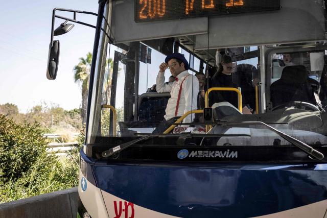 A man in costume for Purim waits on a bus as taking shelter under a bridge after missile sirens sounded in Tel Aviv on March 3, 2026. The United States and Israel started striking Iran on February 28, killing Iran's supreme leader and top military leaders, and prompting authorities to retaliate with strikes on Israel and across the Gulf. (Photo by JOHN WESSELS / AFP)