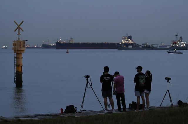 Photographers wait for the full moon, also known as the "Blood Moon", to rise along the coast in Singapore on March 3, 2026. (Photo by Roslan RAHMAN / AFP)