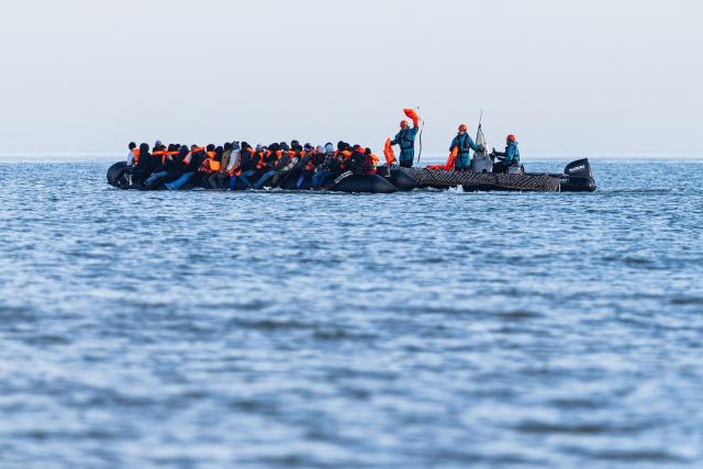 A boat of the French Navy distritbutes life jackets to migrants aboard a smugglers' boat attempting to cross the English Channel off the beach of Gravelines, northern France, on March 3, 2026. At dawn on March 3, 2026, four makeshift boats left the beach at Gravelines, each carrying at least around fifty people, taking advantage of the temporary improvement in weather conditions to attempt an illegal crossing of the English Channel, AFP journalists observed. (Photo by Sameer Al-DOUMY / AFP)
