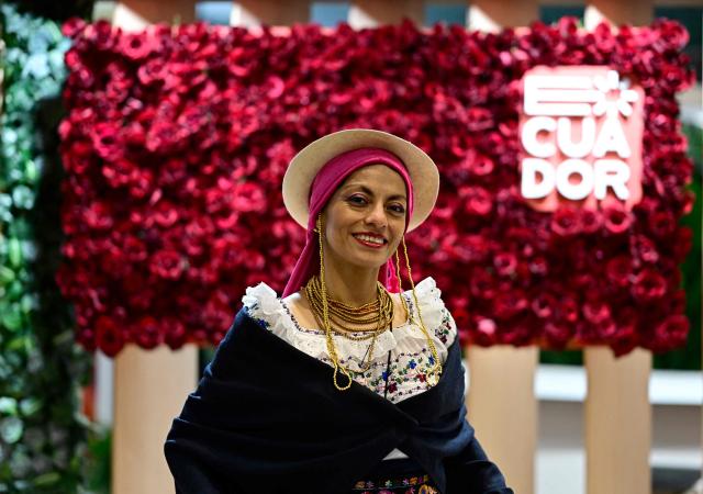 A woman in a traditional dress stands at the booth of Ecuador on the opening day of the ITB (Internationale Tourismus-Boerse) tourism fair in Berlin on March 3, 2026. Around 190 countries are represented at the platform for the global travel and tourism industry running from March 3 to 5, 2026. (Photo by Tobias SCHWARZ / AFP)