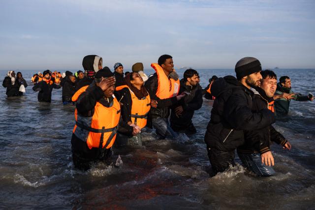 Migrants walk in the water as they try to board a smugglers' boat in an attempt to cross the English Channel off the beach of Gravelines, northern France, on March 3, 2026. At dawn on March 3, 2026, four makeshift boats left the beach at Gravelines, each carrying at least around fifty people, taking advantage of the temporary improvement in weather conditions to attempt an illegal crossing of the English Channel, AFP journalists observed. (Photo by Sameer Al-DOUMY / AFP)