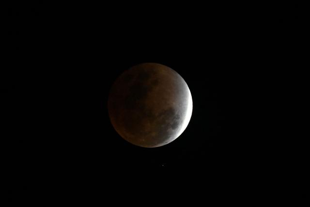 This photograph shows a full moon, also known as the "Blood Moon" during a phase of a total lunar eclipse in Manila on March 3, 2026. (Photo by Ted ALJIBE / AFP)