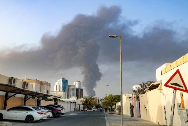 People watch from a street as a tall smoke plume billows following an explosion in the Fujairah industrial zone on March 3, 2026. Iran's strikes on Gulf neighbours since February 28, following the US-Israeli attack, forced the UAE to shut its airspace, blindsiding travellers who thought they were headed to one of the region's safest holiday destinations. (Photo by Fadel SENNA / AFP)
