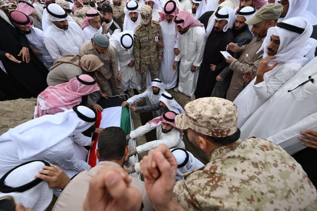 Mourners lift the flag draped body of a Kuwait Army members who were killed in an Iranian strike on Kuwait, into a grave at the Sulaibikhat cemetery, west of Kuwait City on March 3, 2026. The United States and Israel launched strikes against Iran on February 28, with the killing of Iran's supreme leader and the Islamic republic retaliated with barrages of missiles at Gulf states and Israel. (Photo by YASSER AL-ZAYYAT / AFP)