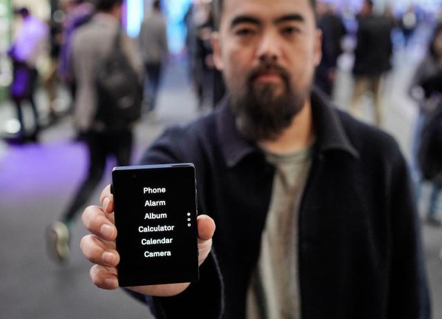 Kaiwei Tang, CEO and Co-founder of Light, poses with a Light Phone III during an AFP interview at the Mobile World Congress (MWC), the world's biggest mobile technology showcase and fair in Barcelona on March 3, 2026. The Mobile World Congress (MWC), the major annual telecommunications event, opened in Barcelona for an edition where Artificial Intelligence in telecommunications will take center stage in the debates. The event, which marks its twentieth anniversary, will host the world's leading telecommunications operators and numerous manufacturers. 109,000 industry professionals and visitors are expected. (Photo by Manaure Quintero / AFP)