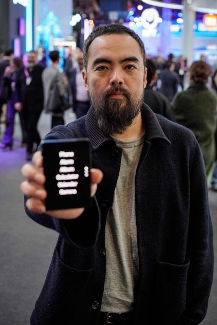 Kaiwei Tang, CEO and Co-founder of Light, poses with a Light Phone III during an AFP interview at the Mobile World Congress (MWC), the world's biggest mobile technology showcase and fair in Barcelona on March 3, 2026. The Mobile World Congress (MWC), the major annual telecommunications event, opened in Barcelona for an edition where Artificial Intelligence in telecommunications will take center stage in the debates. The event, which marks its twentieth anniversary, will host the world's leading telecommunications operators and numerous manufacturers. 109,000 industry professionals and visitors are expected. (Photo by Manaure Quintero / AFP)