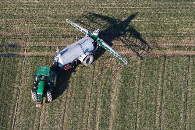 This aerial view shows a farmer spreading liquid manure on a field, in Hede-bazouhes, western France, on March 3, 2026. (Photo by Damien MEYER / AFP)