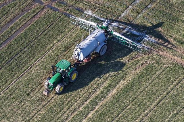 This aerial view shows a farmer spreading liquid manure on a field, in Hede-bazouhes, western France, on March 3, 2026. (Photo by Damien MEYER / AFP)