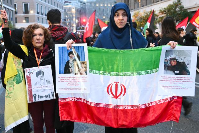 Women hold pictures of assassinated Iranian supreme leader Ayatollah Ali Khamenei and an Iranian flag during a protest against the US and Israel attack of Iran near the US Embassy in Rome, on March 3, 2026. The United States and Israel launched strikes against Iran on February 28, killing Iran's supreme leader and top military leaders, prompting authorities to retaliate with strikes on Israel and across the Gulf. (Photo by Alberto PIZZOLI / AFP)
