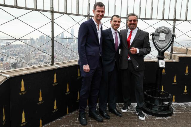 CEO and Secretary General of US Soccer Federation JT Batson (L), CEO of FIFA World Cup 26 New York New Jersey Host Committee Alex Lasry (C), and President of Canada Soccer Peter Augruso (R) pose at the top of the Empire State Building to celebrate 100 days until the World Cup in New York on March 3, 2026, The 100-day countdown to the biggest World Cup in history gets under way on Tuesday against a chaotic backdrop of global unrest, from US-Israeli strikes on Iran to surging violence in Mexico and anxiety over Donald Trump's domestic agenda. A record 48 teams and millions of fans are set to descend on the United States, Canada and Mexico for the first ever World Cup shared by three nations. (Photo by CHARLY TRIBALLEAU / AFP)