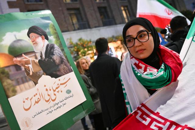A woman hold a picture of assassinated Iranian supreme leader Ayatollah Ali Khamenei during a protest against the US and Israel attack of Iran near the US Embassy in Rome, on March 3, 2026. The United States and Israel launched strikes against Iran on February 28, killing Iran's supreme leader and top military leaders, prompting authorities to retaliate with strikes on Israel and across the Gulf. (Photo by Alberto PIZZOLI / AFP)