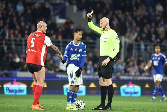 French referee Eric Watellier gives a yellow card to Reims’ French defender #05 Nicolas Pallois (L) during the French Cup quarter final football match between RC Strasbourg Alsace and Stade de Reims at the Stade de la Meinau in Strasbourg, eastern France, on March 3, 2026. (Photo by Frederick FLORIN / AFP)