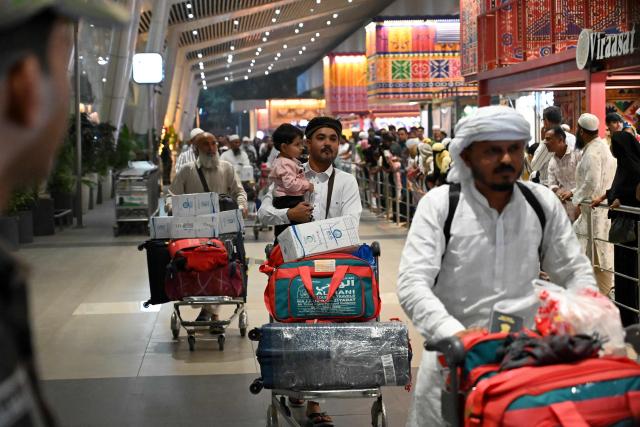 Indian Muslim passengers arrive at the airport of Ahmedabad on late March 3, 2026, after they were stranded in Jeddah (Saudi Arabia) as they visited for special prayer in ongoing Ramadan month, following the eruption of a regional conflict sparked by Israel-US strikes on Iran. Governments and airlines scrambled on March 3, 2026 to repatriate tens of thousands of travellers stranded in the Middle East. (Photo by Shammi MEHRA / AFP)
