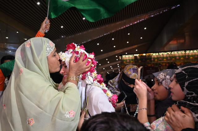 TOPSHOT - Indian Muslim passengers are welcomed upon arrival at the airport of Ahmedabad on late March 3, 2026, after they were stranded in Jeddah (Saudi Arabia) as they visited for special prayer in ongoing Ramadan month, following the eruption of a regional conflict sparked by Israel-US strikes on Iran. Governments and airlines scrambled on March 3, 2026 to repatriate tens of thousands of travellers stranded in the Middle East. (Photo by Shammi MEHRA / AFP)