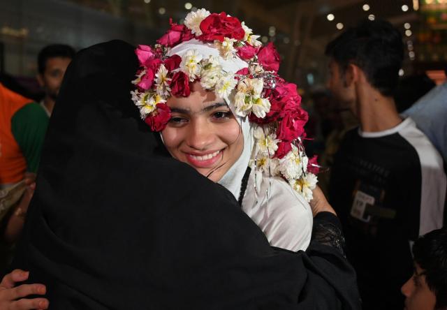 An Indian Muslim passenger is welcomed upon their arrival at the airport of Ahmedabad on late March 3, 2026, after she was stranded in Jeddah (Saudi Arabia) as she visited for special prayer in ongoing Ramadan month, following the eruption of a regional conflict sparked by Israel-US strikes on Iran. Governments and airlines scrambled on March 3, 2026 to repatriate tens of thousands of travellers stranded in the Middle East. (Photo by Shammi MEHRA / AFP)