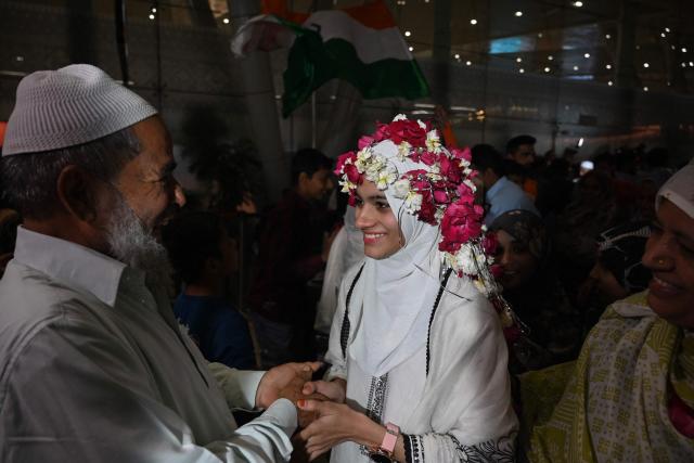 Indian Muslim passengers are welcomed upon their arrival at the airport of Ahmedabad on late March 3, 2026, after they were stranded in Jeddah (Saudi Arabia) as they visited for special prayer in ongoing Ramadan month, following the eruption of a regional conflict sparked by Israel-US strikes on Iran. Governments and airlines scrambled on March 3, 2026 to repatriate tens of thousands of travellers stranded in the Middle East. (Photo by Shammi MEHRA / AFP)
