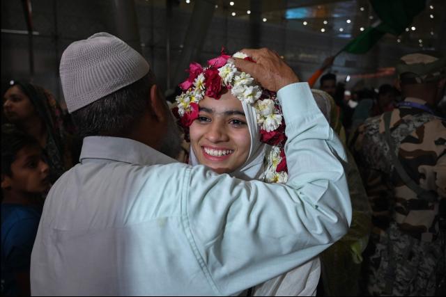 An Indian Muslim passenger is welcomed upon their arrival at the airport of Ahmedabad on late March 3, 2026, after she was stranded in Jeddah (Saudi Arabia) as she visited for special prayer in ongoing Ramadan month, following the eruption of a regional conflict sparked by Israel-US strikes on Iran. Governments and airlines scrambled on March 3, 2026 to repatriate tens of thousands of travellers stranded in the Middle East. (Photo by Shammi MEHRA / AFP)