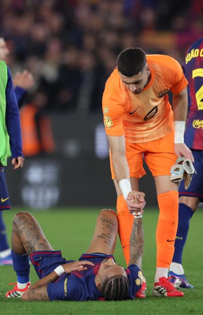 Barcelona's Spanish goalkeeper #13 Joan Garcia helps Barcelona's Brazilian forward #11 Raphinha to stand up during the Copa del Rey (King's Cup) semi final second leg football match between FC Barcelona and Club Atletico de Madrid at Camp Nou Stadium in Barcelona on March 3, 2026. (Photo by Josep LAGO / AFP)