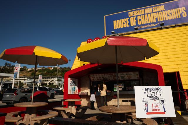 An America’s 250th anniversary hat sign is displayed as customers wait for food orders outside the Wienerschnitzel American hot dog and fast food restaurant in Los Angeles, on March 2, 2026. (Photo by Patrick T. Fallon / AFP)