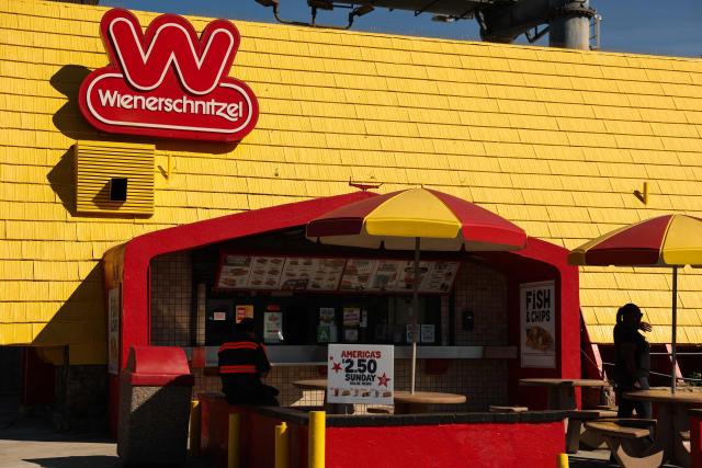 An America’s 250th special sign is displayed as customers wait for food orders outside the Wienerschnitzel American hot dog and fast food restaurant in Los Angeles, on March 2, 2026. (Photo by Patrick T. Fallon / AFP)