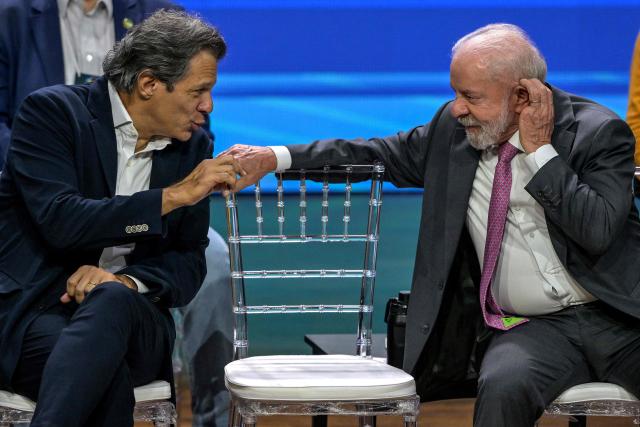 Brazil's Finance Minister Fernando Haddad (L) and President Luiz Inacio Lula da Silva (R) talk during the opening ceremony of the National Labor Conference in Sao Paulo, Brazil on March 3, 2026. (Photo by Nelson ALMEIDA / AFP)
