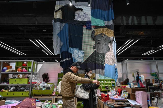 The photo taken on February 10, 2026 shows people browsing through products at a second-hand store in Shanghai. Boosting domestic consumption will be among key goals set forth by China's leaders at the annual Two Sessions political conclave this week, but they face an uphill battle. (Photo by Jade GAO / AFP) / To go with AFP story:  China-economy-politics-consumer-travel-retail, FOCUS by Jing Xuan TENG and Peter CATTERALL